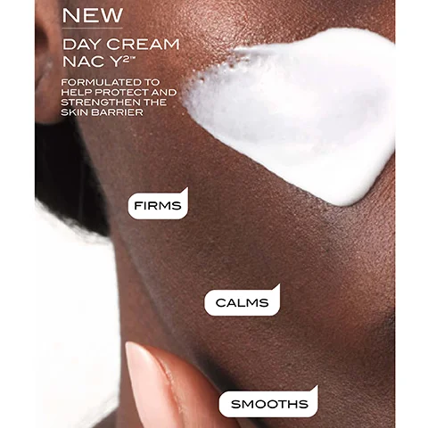 A close-up image of a hand applying a white cream onto dark skin, with text labels indicating benefits: NEW, DAY CREAM NAC Y™, FORMULATED TO HELP PROTECT AND STRENGTHEN THE SKIN BARRIER, FIRMS, CALMS, SMOOTH.