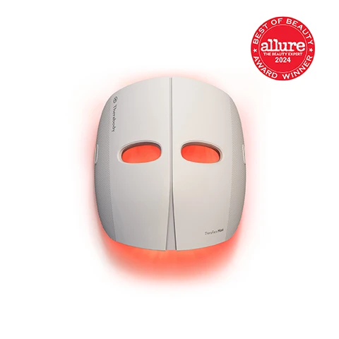 Image 2 - A white LED light therapy face mask with red light emanating from behind, featuring the text Therabody on its side, TheraFace Mask near the bottom, and a red circular badge in the upper right that reads BEST OF BEAUTY allure THE BEAUTY EXPERT 2024 AWARD WINNER. Image 3 - A woman holds a white TheraFace Mask emitting red light onto her face, with text on the left stating Clinically-proven LED light therapy, Reduces wrinkles, Firms & contours, Improves radiance, and Evens skin tone. Image 4 - A before and after comparison image of a persons lower face and neck shows a less defined jawline with loose skin in the Before image on the left and a more defined, tighter jawline in the After image on the right, with white boxes highlighting the area of change; visible text includes Before, After, Unretouched. 1x/day use for 12 weeks*, 93% of study participants saw improvements in the appearance of full face lines*, and *Perception survey results based on a 12-week study with 31 subjects and 1x/day use of the pre-programmed treatment. Learn more at therabody.com/science. Image 5 - A white LED facial mask with red lights glowing is prominently displayed on an orange surface, accompanied by three circular images below showing close-ups of the mask emitting red, pink, and blue lights, along with the text: Results in weeks from just 9 minutes daily, TheraFace Mask, Red Light Firms skin and reduces fine lines and wrinkles, Red + Infrared LED Light Reduces dark spots and improves radiance, Blue Light Fights acne and acne-causing bacteria. Image 6 - A split image shows a woman with her face covered in many red and white LED lights representing the TheraFace Mask on the left, and the same woman with fewer red and white LED lights on her face representing a Competitor Mask on the right, with the text 3x more LED lights than the leading mask competitor 648 lights deliver maximum efficacy and results in the shortest time *Based on 2024 sales data. Image 7 - A woman relaxes on a couch wearing a white light therapy mask with red light glowing around her face and neck, holding a black remote control, with overlay text Cordless, handsfree design, Allows for convenient multi-tasking and TheraFace Mask on the mask. Image 8 - A woman wears a white TheraFace Mask emitting red light around her face and neck, with blue vibration waves on her forehead, while an inset shows the masks grey strap and internal vibration mechanism, and the image includes the text Gentle vibration therapy, Scalp and facial massage relieve tension and promote relaxation, and TheraFace Mask.