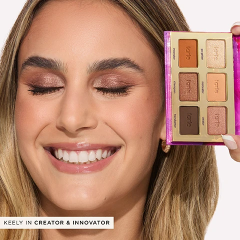 Image 1 - A smiling woman with long hair holds a makeup palette featuring six shades, including visible text for innovator, go getter, champion, motivator, trendsetter, and creator on the palette.
Image 2 - Swatches of six eyeshadow shades from the Tartelette In Bloom Mini Amazonian Clay Palette on three different skin tones, with visible text indicating the shade names and numbers: 1. GO GETTER, 2. MOTIVATOR, 3. CREATOR, 4. INNOVATOR, 5. CHAMPION, 6. TRENDSETTER.
Image 3 - Close-up portrait of a woman with long dark hair and warm makeup, featuring visible text that reads SYDNEY IN TRENDSETTER, INNOVATOR & GO-GETTER.
Image 4 - A makeup palette with a full-size section on top labeled with shades like charmer, jetsetter, and smokeshow, and a travel-size section below featuring shades like innovator, champion, and trendsetter, with arrows indicating full-size and travel-size.