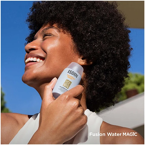 Image 1 - A smiling woman with curly hair holds a bottle of sunscreen close to her face, showcasing healthy skin, with the text Fusion Water MAGIC and ISDIN visible on the bottle.
Image 2 - A close-up of a woman resting her face on her arm, looking at the camera with a jar of ISDIN Hyaluronic Eyes placed on her forearm. Visible text includes ISDIN, ISDINCEUTICS, and HYALURONIC EYES.
Image 3 - A hand is holding a light blue bottle of skincare product, pouring a creamy liquid onto the palm with the text Fusion Water MAGIC visible at the bottom.
Image 4 - A silver and gold eye treatment applicator rests on a glossy gel-like substance, with the label ISDINCEUTICS visible on the handle, and the text HYALURONIC EYES appears at the bottom left.
