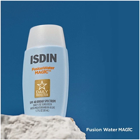 Image 1 - A light blue bottle of ISDIN Fusion Water MAGIC sunscreen, featuring a white cap, against a blue background, with text that reads SPF 40 BROAD SPECTRUM DAILY LITE SUNSCREEN WITH MEDITERRANEAN ALGAE and Fusion Water MAGIC.
Image 2 - A white tube of ISDIN K-Ox Eyes eye cream with a gold cap is placed on a bed of ice, with the product name and brand visible at the bottom.
Image 3 - A woman with long brown hair smiles while applying a skincare product to her cheek, with a clear blue sky in the background; visible text reads Fusion Water MAGIC.
Image 4 - A woman with blonde hair smiles while applying a small amount of cream under her left eye, with a light background; K-Ox Eyes is displayed in the bottom right corner.