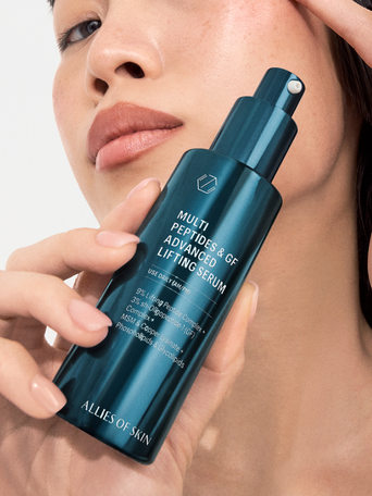 A person applying the Allies of Skin Multi Peptides & GF Advanced Lifting Serum from a sleek teal bottle with a black pump, designed to visibly lift and firm the complexion.